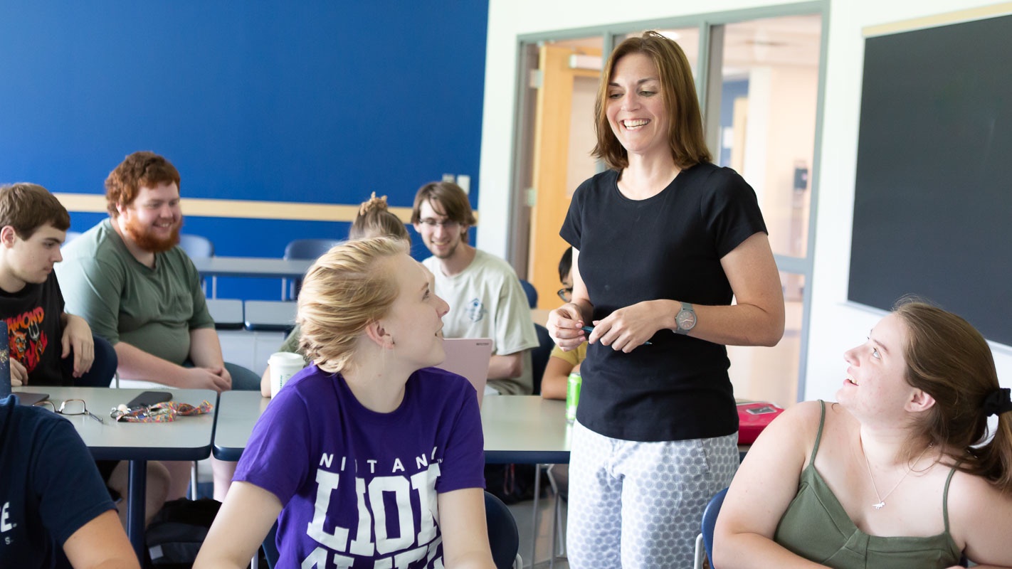 Teacher speaking with students in a college classroom